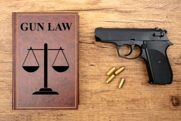 a book titled 'gun law' is sitting on a table beside a gun and four bullets