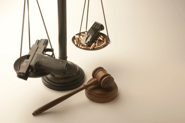 semi-automatic pistol, magazine and bullets on scales of justice with judge's gavel