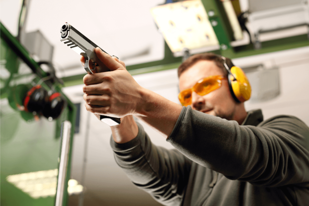 Man shooting a firearm at a shooting range, wearing protective eyewear and hearing protection