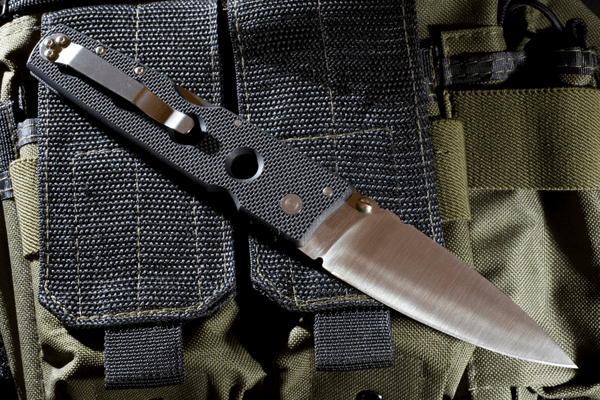 tactical folding knife placed on top of nylon gear