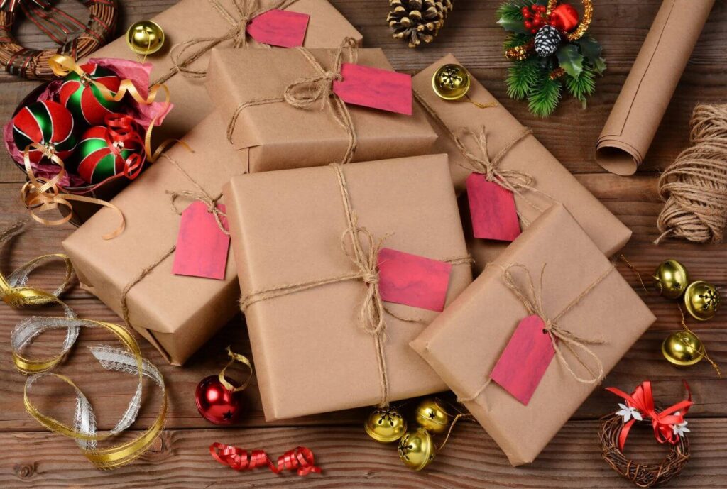 holiday gifts wrapped with brown paper and twine surrounded by holiday ornaments
