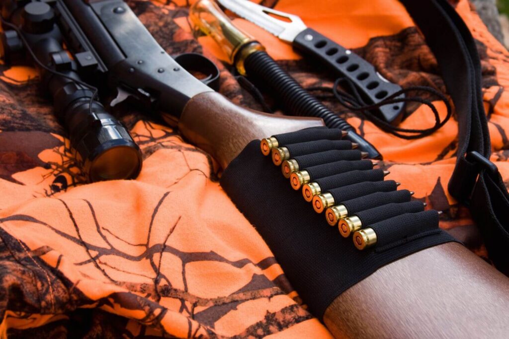 An assortment of hunting supplies laying on top of orange camouflage fabric