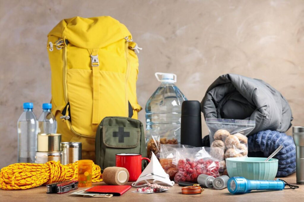 A yellow bug out bag and emergency survival gear are displayed on a table