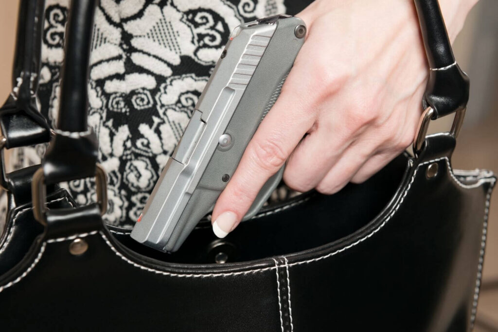 Woman Pulling a Small Caliber Handgun out of a Black Purse