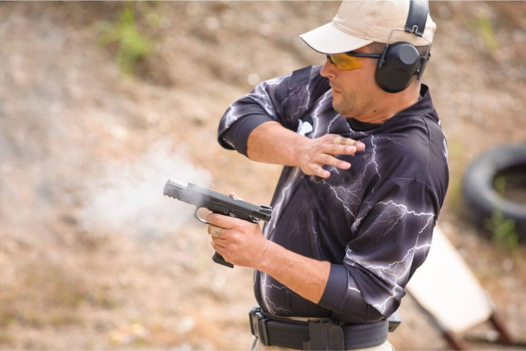 man wearing protective earwear during a firearm training session at an outdoor shooting range
