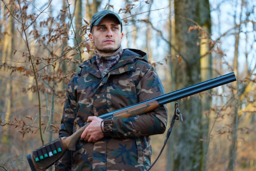 Man Standing in the Woods Holding a Rifle and Wearing Camouflage Clothing