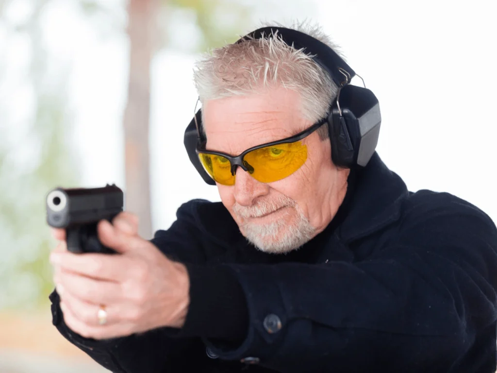 Elderly Man Shooting a Firearm at an Outdoor Gun Range