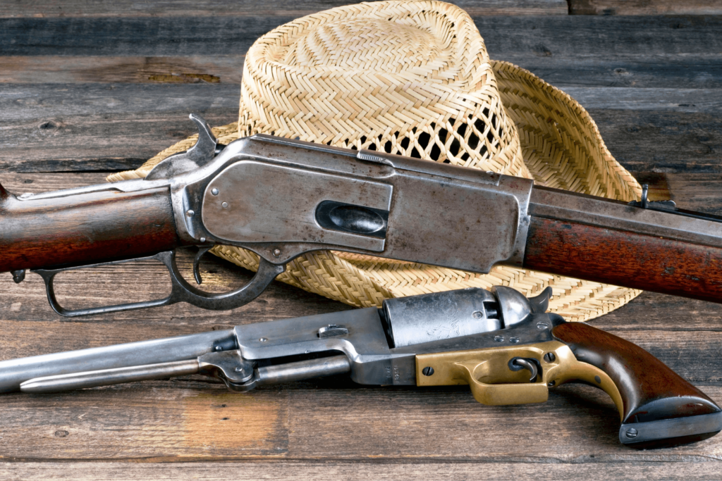 A wooden table with two antique firearms and a straw hat placed on it - Pennsylvania Gun Shows | Get Tickets For Eagle Shows a Wooden Table with Two Antique Firearms and a Straw Hat Placed on It