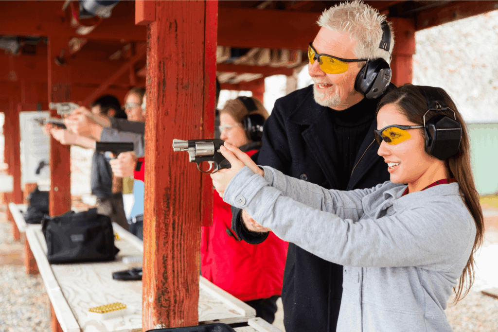 a Man and a Woman at a Gun Range Wearing Protective Ear and Eye Wear the Woman is Holding a Firearm