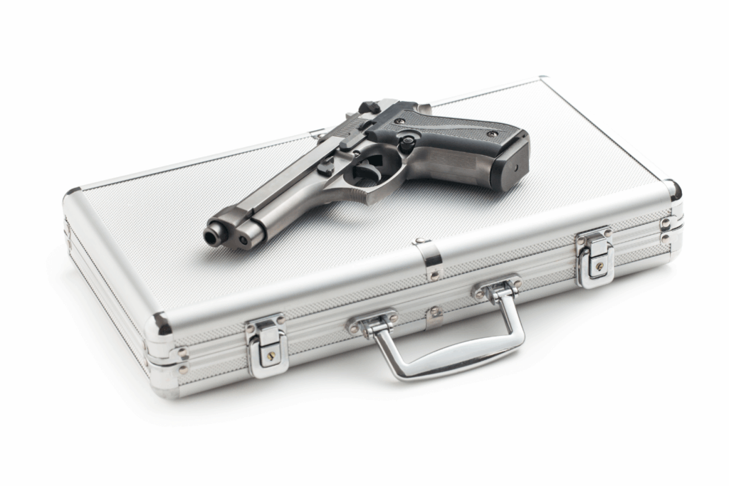 a Large Hard Silver Gun Case Closed with a Gun Lying on Top of It