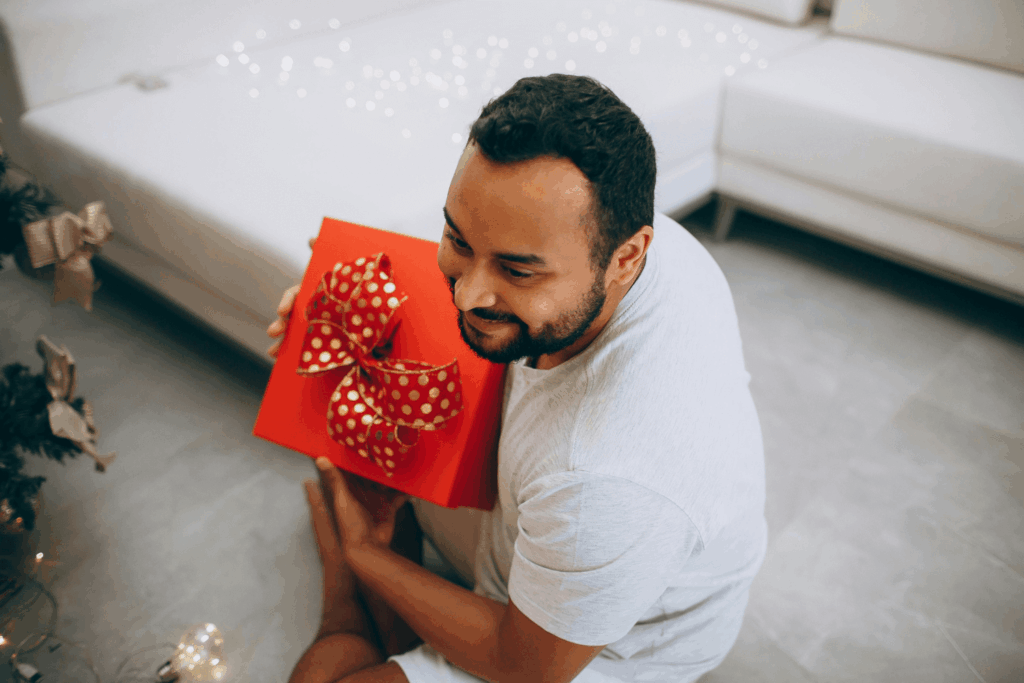Man Sitting on the Ground Holding a Red Gift Box