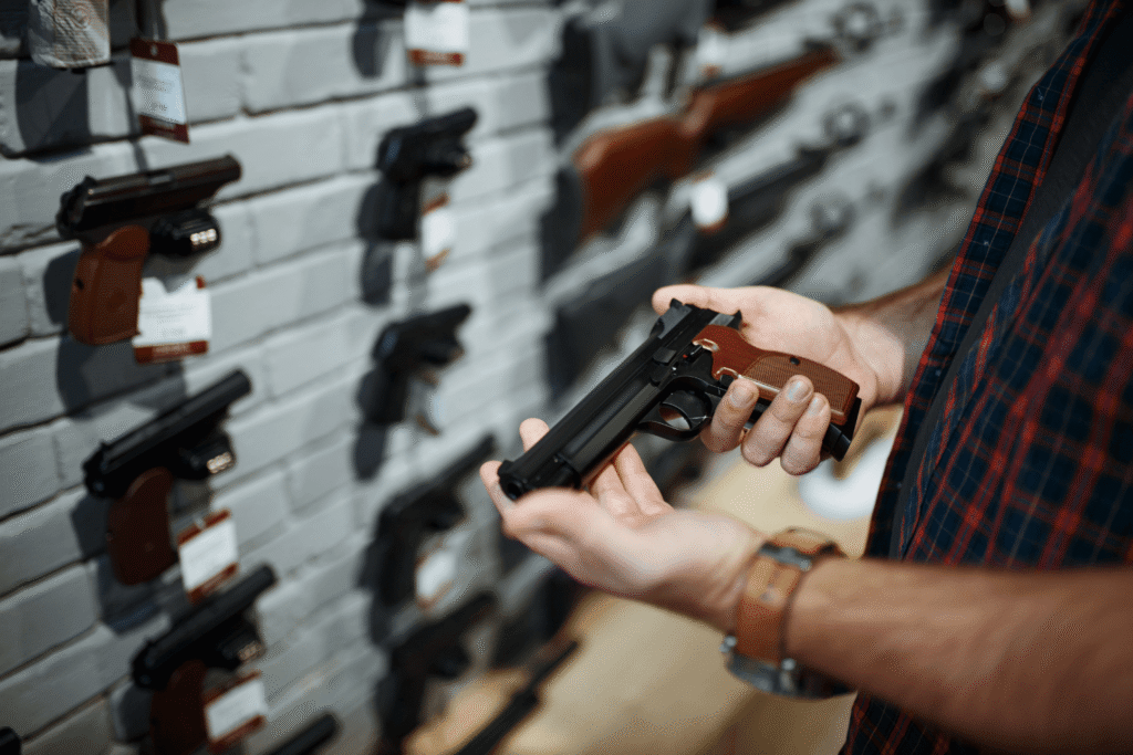 Man Holding a Pistol As He Inspects It Before Buying