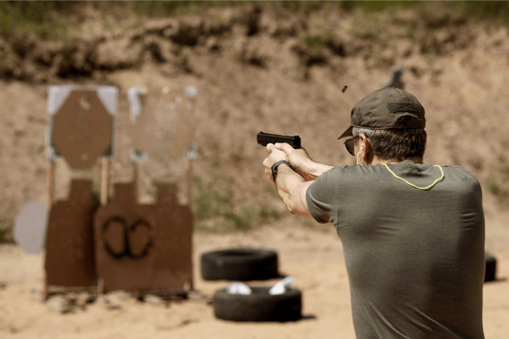 a Man Dressed in Black Holding a Gun and Aiming at a Target at an Outdoor Shooting Range