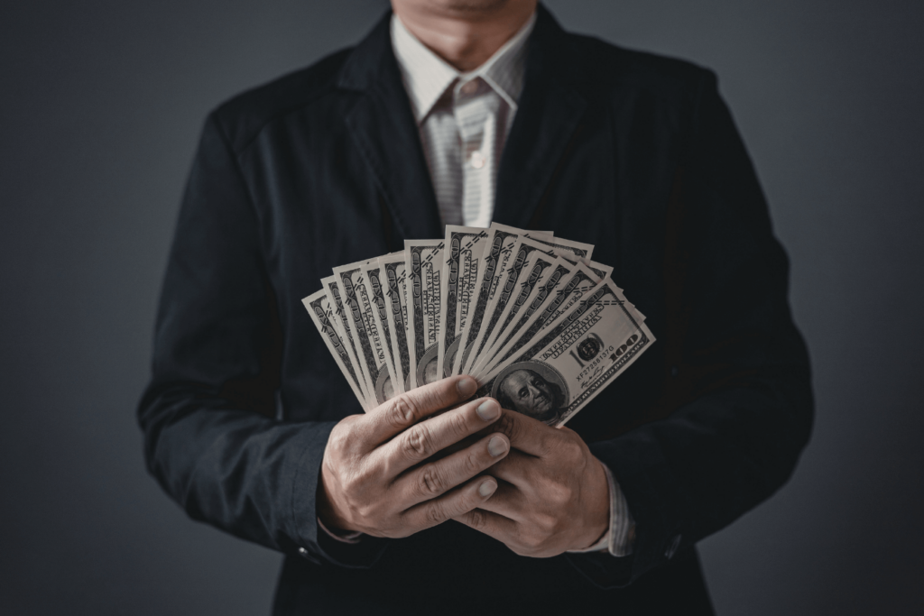 a Person in a Black Suit Jacket Holding Fanned out Hundred dollar Bills